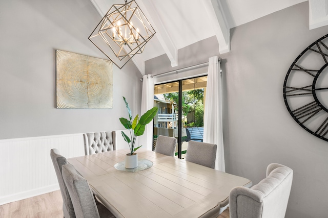 dining room with light wood-type flooring, a chandelier, and beam ceiling