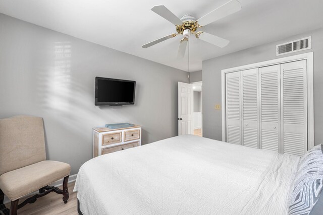 bedroom featuring light hardwood / wood-style flooring, ceiling fan, and a closet