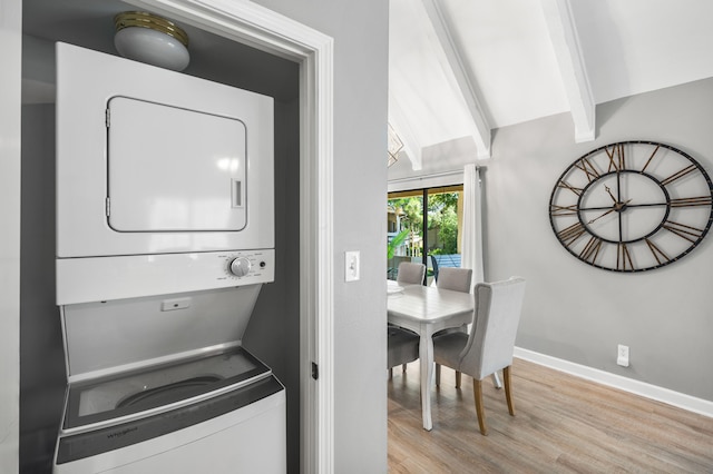 laundry room with light wood-type flooring and stacked washer / dryer