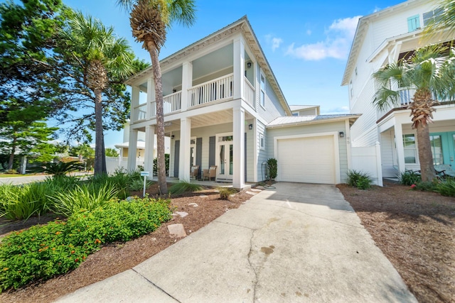 view of front of house with a balcony, a porch, an attached garage, concrete driveway, and french doors