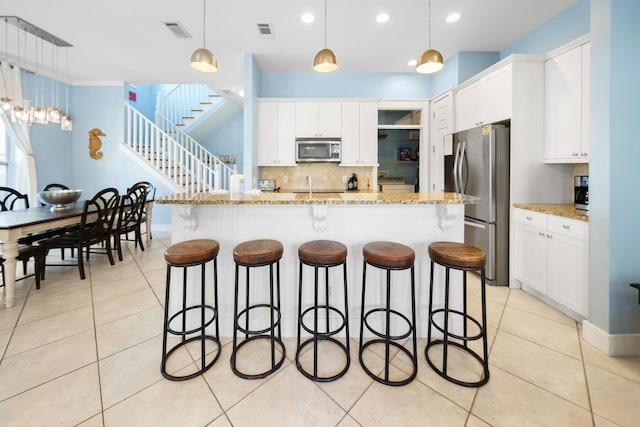 kitchen with a sink, a kitchen breakfast bar, visible vents, and stainless steel appliances