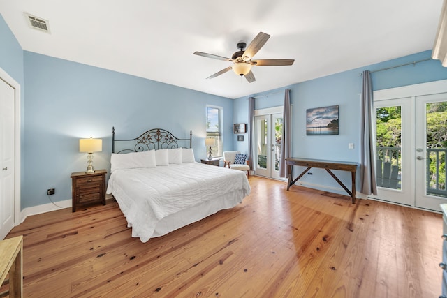 bedroom featuring baseboards, multiple windows, light wood-style floors, and access to exterior