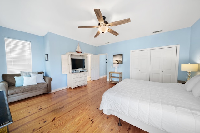 bedroom featuring wood finished floors, visible vents, baseboards, ceiling fan, and a closet