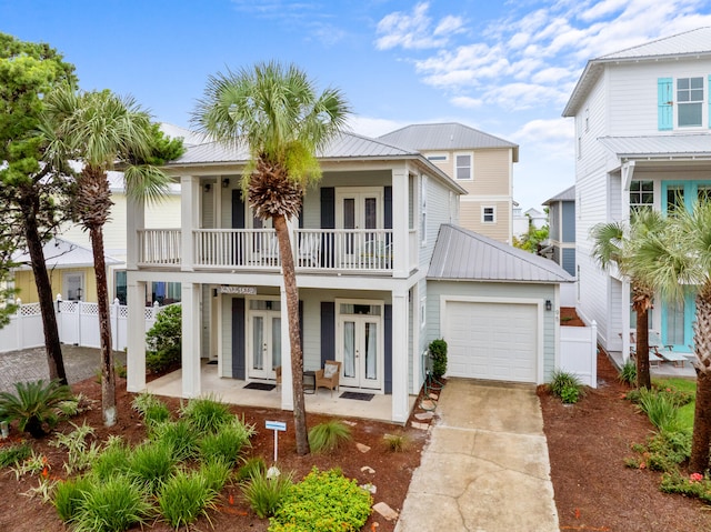 view of front of house with french doors, metal roof, driveway, a balcony, and an attached garage