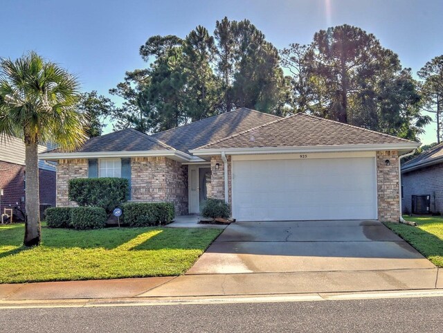 ranch-style house featuring a shingled roof, concrete driveway, a garage, cooling unit, and a front lawn