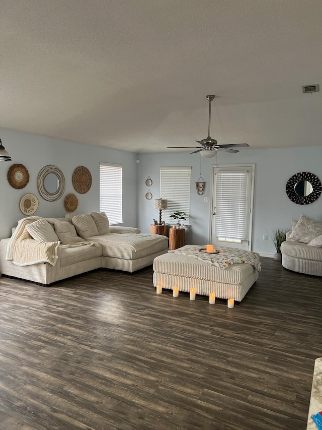 living room with a textured ceiling, ceiling fan, and dark hardwood / wood-style floors