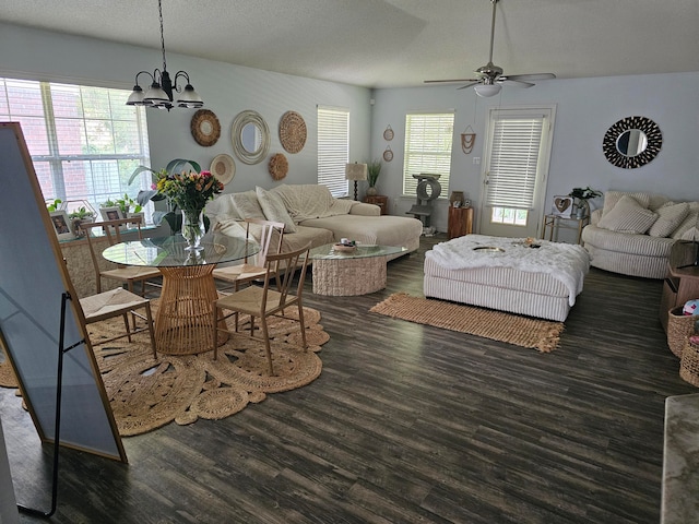 living room with ceiling fan with notable chandelier, a textured ceiling, and dark hardwood / wood-style floors