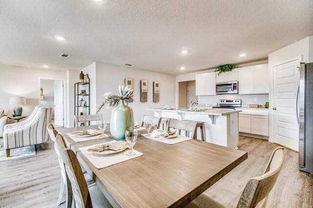 6324 Firefly Dr, Milton, FL 32583 - dining room with light wood-style floors, a textured ceiling, and recessed lighting