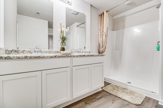 6324 Firefly Dr, Milton, FL 32583 - bathroom featuring wood finished floors, walk in shower, a textured ceiling, and double vanity