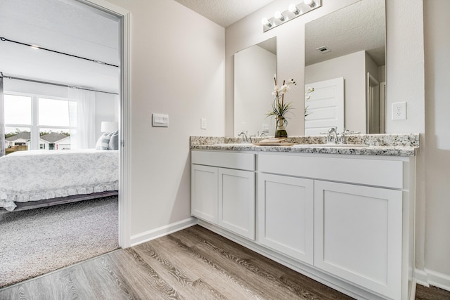 6324 Firefly Dr, Milton, FL 32583 - full bath with ensuite bath, wood finished floors, double vanity, baseboards, and a textured ceiling