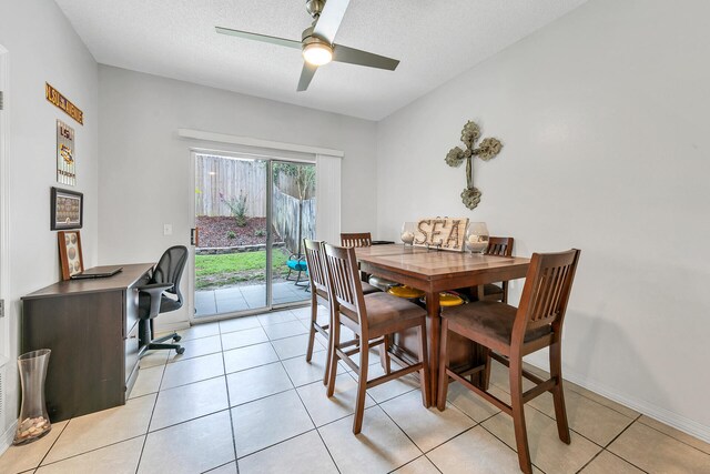 tiled dining space with a textured ceiling and ceiling fan