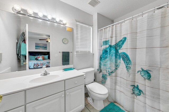 bathroom with ceiling fan, vanity, a textured ceiling, tile patterned floors, and toilet