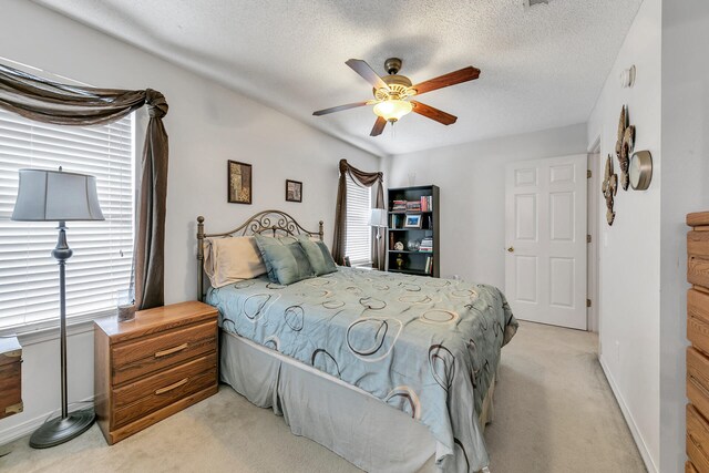 bedroom featuring ceiling fan, light colored carpet, and a textured ceiling