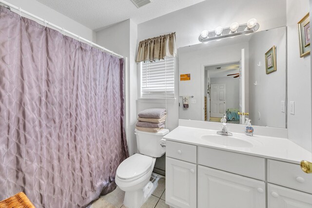 bathroom with ceiling fan, vanity, a textured ceiling, tile patterned floors, and toilet