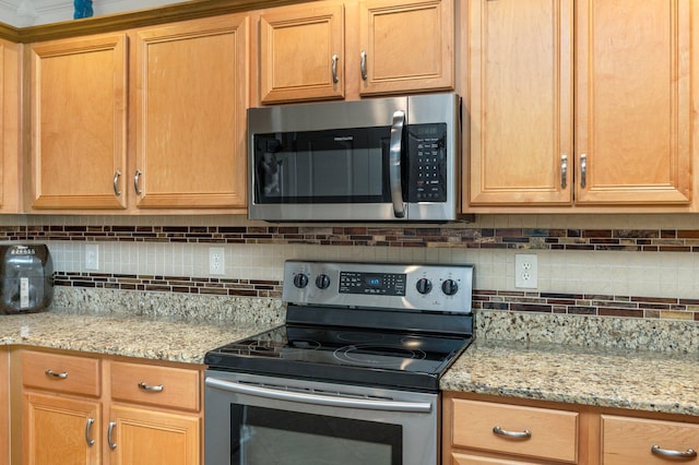 kitchen featuring light stone counters, appliances with stainless steel finishes, and tasteful backsplash