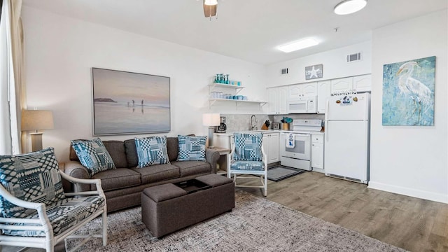 living room with light wood-type flooring, sink, and ceiling fan