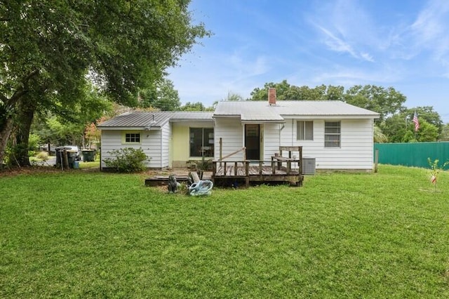 back of house featuring a deck, a yard, fence, and metal roof