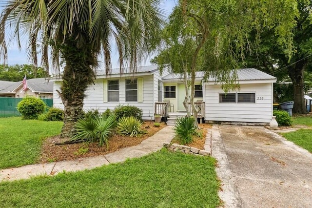 ranch-style home featuring metal roof, driveway, and a front lawn