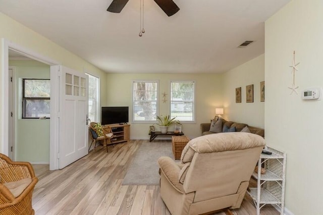 living area featuring baseboards, visible vents, light wood-type flooring, and ceiling fan