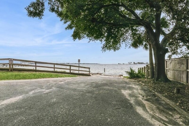 view of yard featuring a water view, a boat dock, and fence