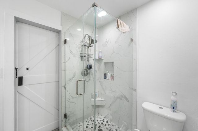 bathroom with toilet and a shower with shower door