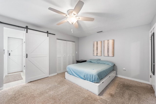 bedroom featuring a barn door, a closet, ceiling fan, and carpet flooring