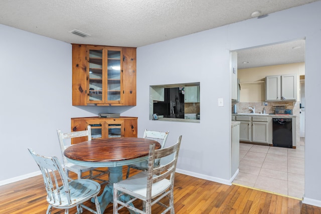 dining space with a textured ceiling, sink, and light hardwood / wood-style floors