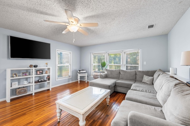 living room with a textured ceiling, ceiling fan, and dark hardwood / wood-style flooring