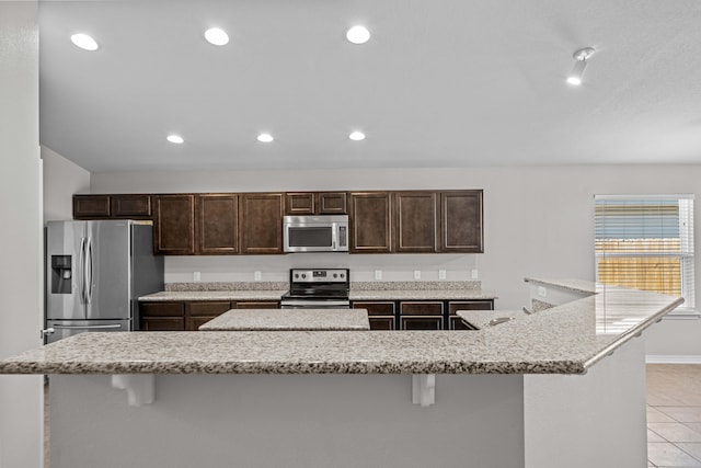 kitchen with a breakfast bar, light tile patterned flooring, a spacious island, and appliances with stainless steel finishes