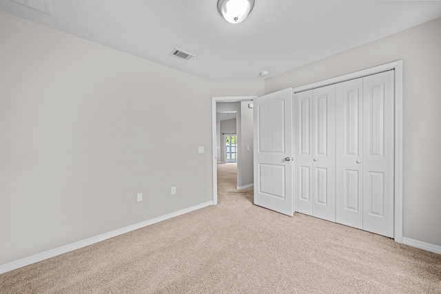 unfurnished bedroom featuring a closet and light colored carpet