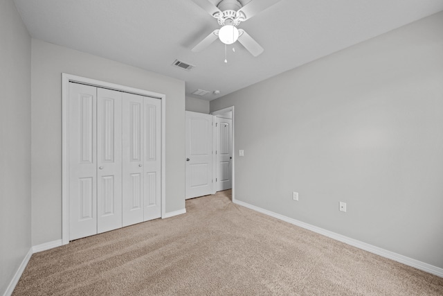 unfurnished bedroom with ceiling fan, light colored carpet, and a closet