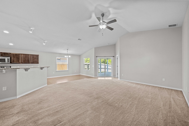 unfurnished living room with light carpet, ceiling fan with notable chandelier, and lofted ceiling