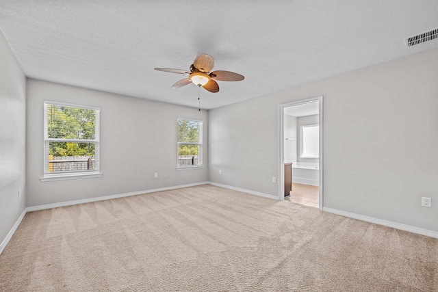 carpeted empty room featuring ceiling fan, a healthy amount of sunlight, and a textured ceiling