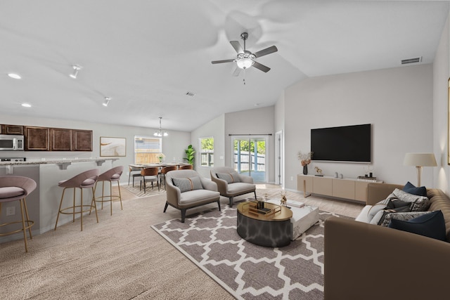 carpeted living room with ceiling fan with notable chandelier and lofted ceiling