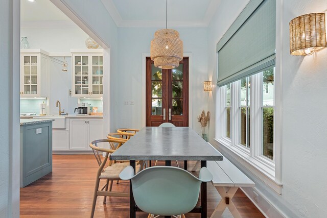 dining space with light wood-type flooring, crown molding, and sink