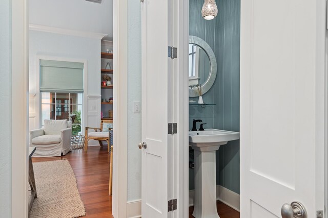 bathroom featuring hardwood / wood-style flooring, crown molding, and sink