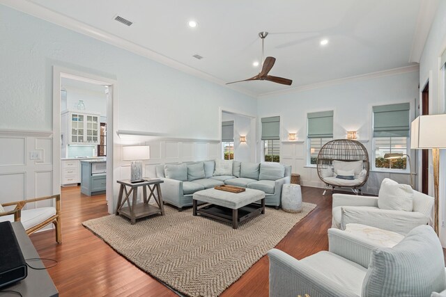 living room featuring dark wood-type flooring, ceiling fan, and ornamental molding