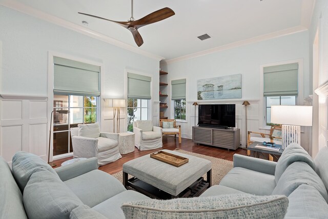 living room featuring crown molding, a fireplace, hardwood / wood-style flooring, and ceiling fan