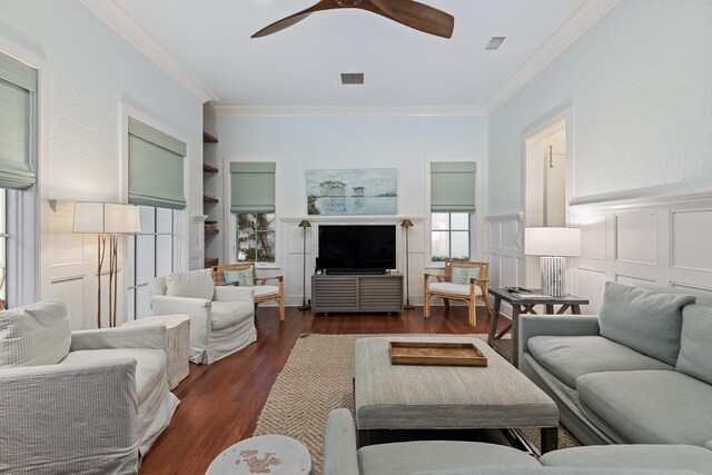 living room featuring built in features, ceiling fan, dark hardwood / wood-style flooring, and crown molding