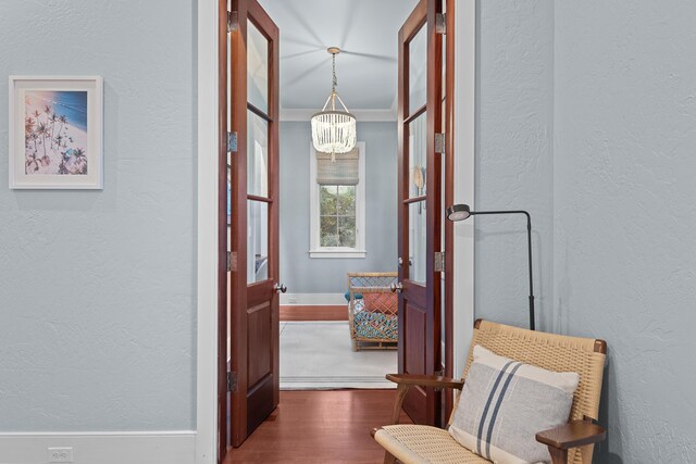 corridor featuring crown molding, dark hardwood / wood-style flooring, and a chandelier