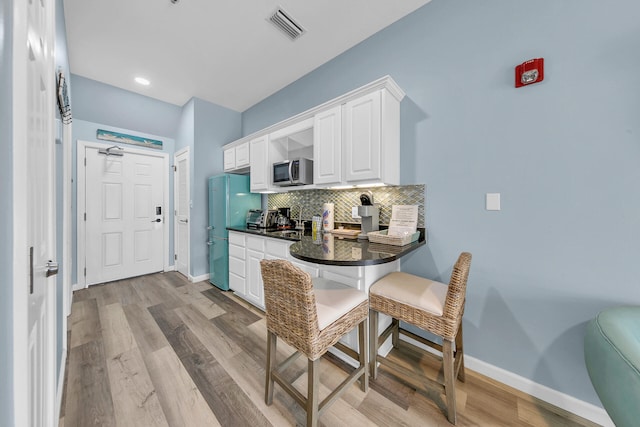 kitchen with white cabinetry, light hardwood / wood-style flooring, and tasteful backsplash