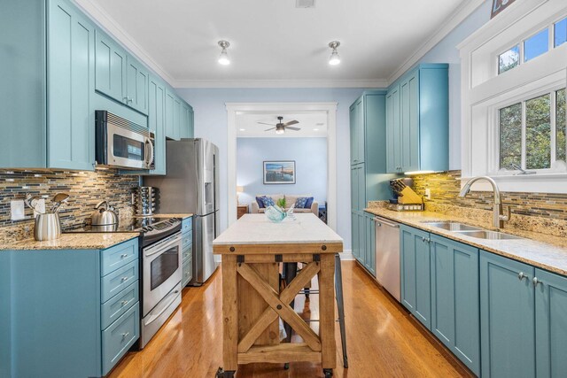 kitchen featuring appliances with stainless steel finishes, backsplash, ceiling fan, sink, and blue cabinetry