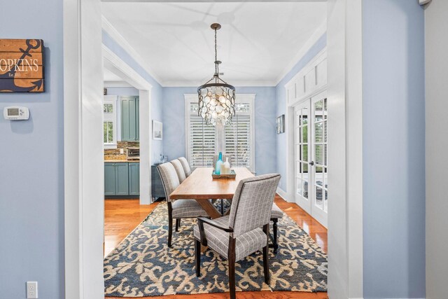 dining room featuring crown molding, light hardwood / wood-style floors, and a notable chandelier