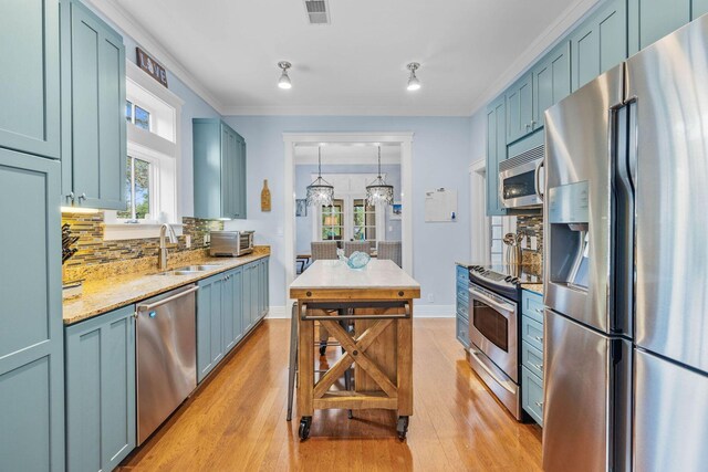 kitchen with decorative backsplash, stainless steel appliances, blue cabinets, crown molding, and hanging light fixtures