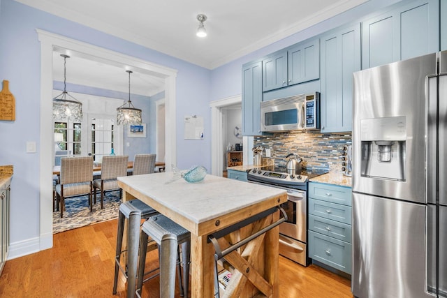 kitchen featuring light stone countertops, appliances with stainless steel finishes, backsplash, blue cabinetry, and hanging light fixtures