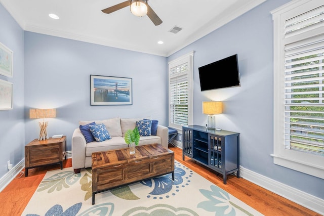 living room with light hardwood / wood-style floors, ceiling fan, and ornamental molding