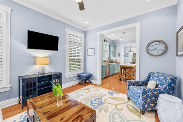 living room with light wood-type flooring, ceiling fan, ornamental molding, and sink