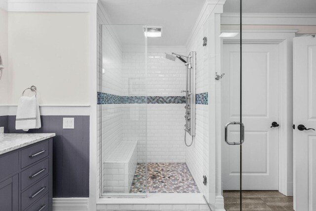 bathroom featuring a shower with door, vanity, hardwood / wood-style floors, and ornamental molding