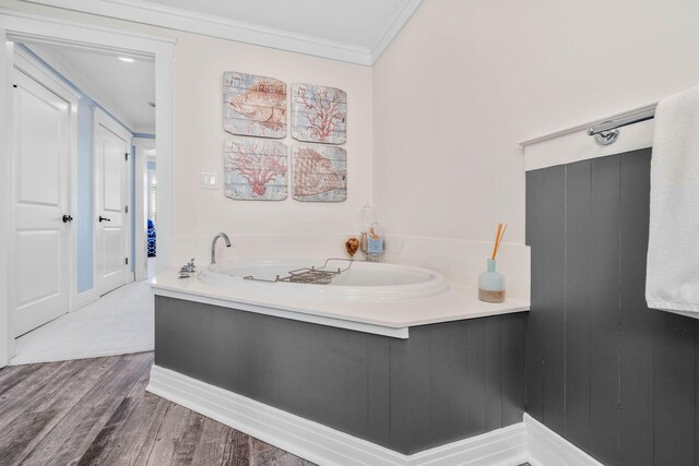 bathroom with a tub, hardwood / wood-style flooring, and ornamental molding