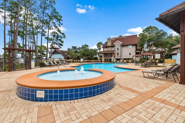 view of swimming pool with pool water feature and a patio